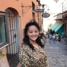 Image: photo of Qi Zhang, who stands in front of an outdoor shop.