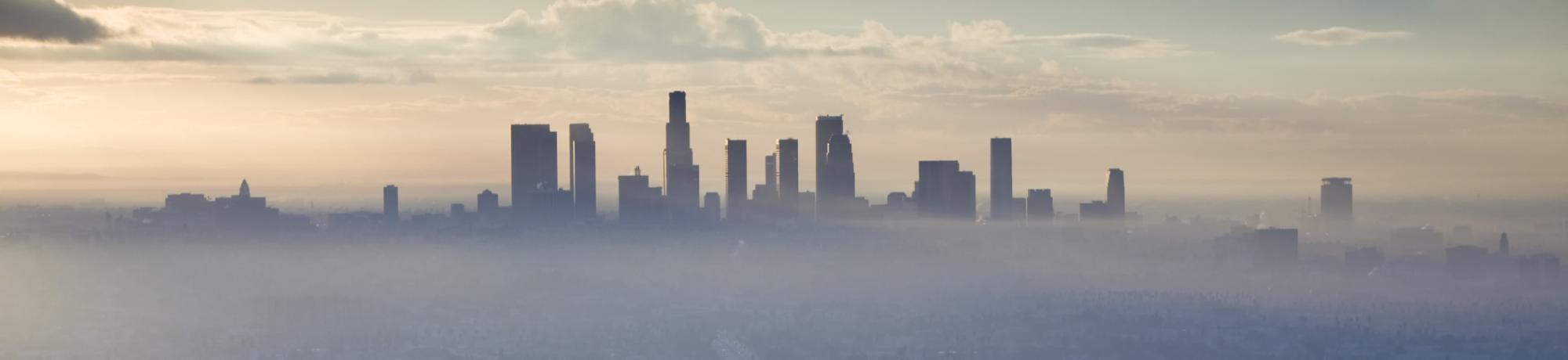 Image: a cityscape enveloped by air pollution.