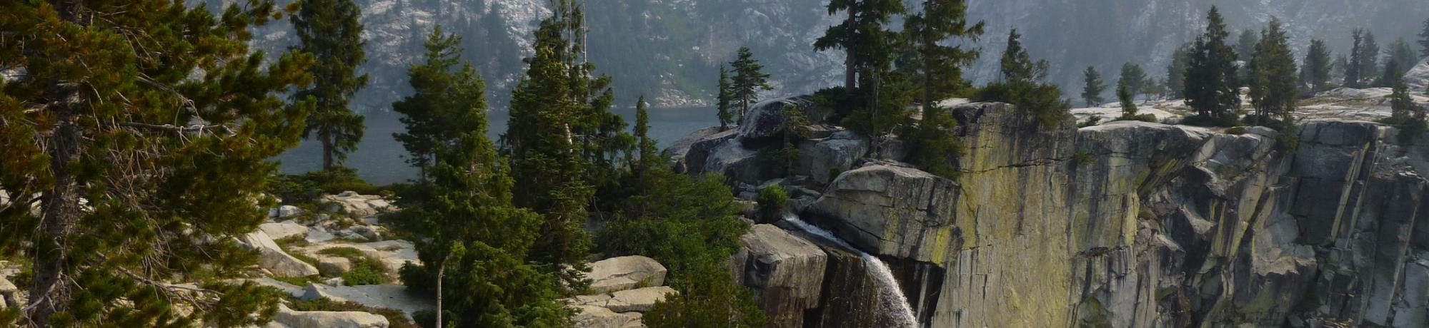 Image: photo of a waterfall emerging from a tree-lined cliff face. Photo taken by Josh Grant of AQRC.